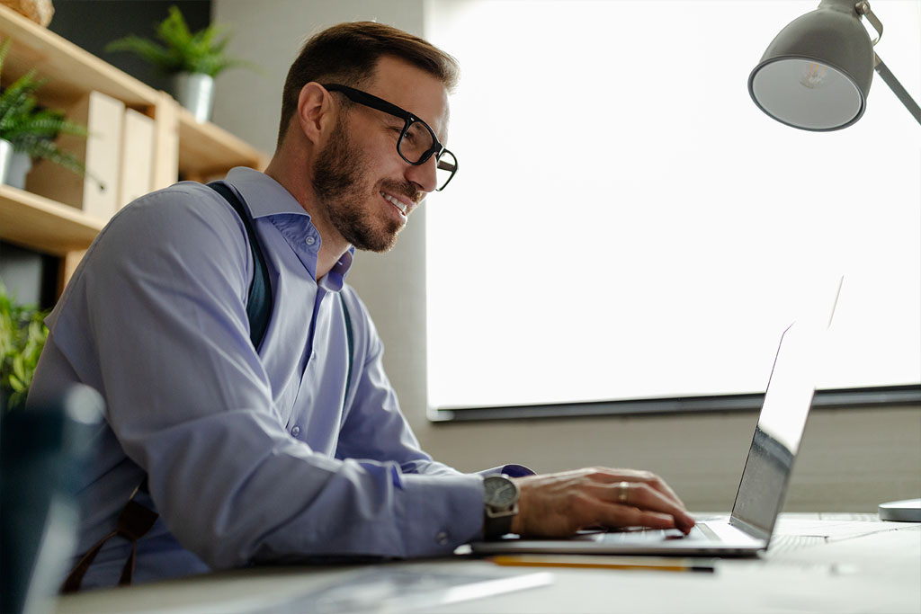 Man sits at computer to send invoices and communicate with his client.